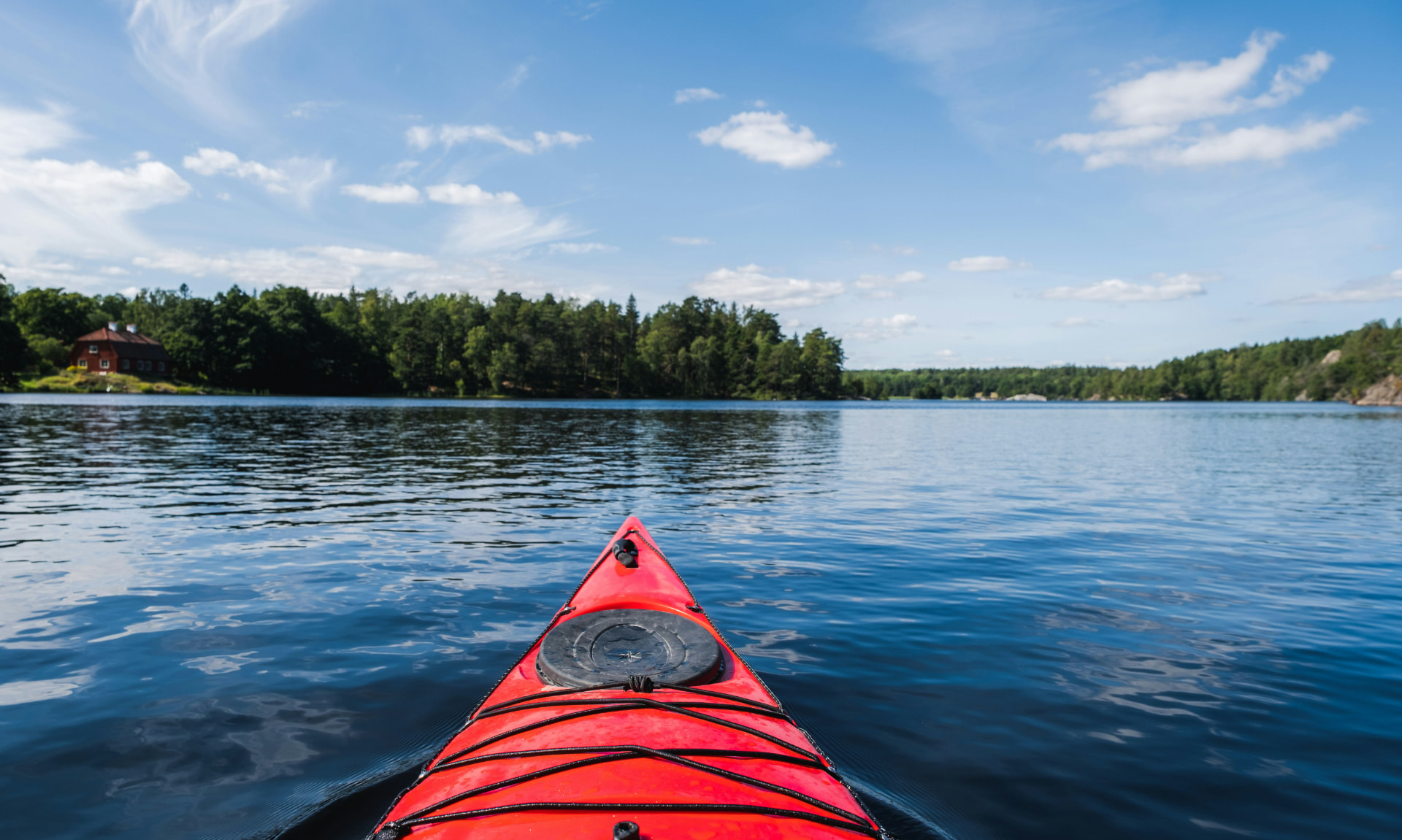 Proue d’un kayak rouge glissant sur l’eau bleue de l’archipel par une journée ensoleillée